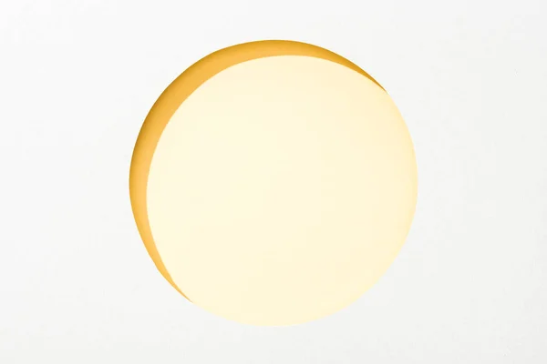 Cut out round hole in white paper on yellow background — Stock Photo