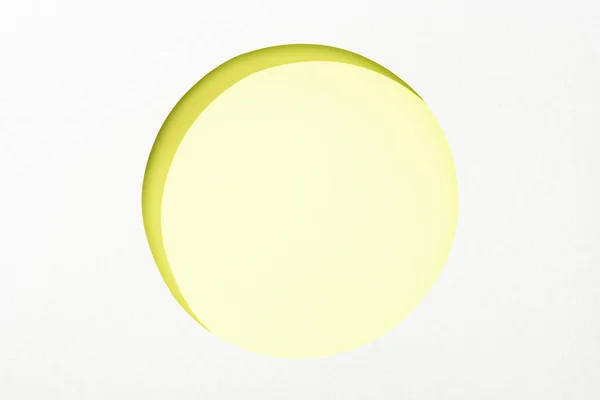 Cut out round hole in white paper on lime green colorful background — Stock Photo