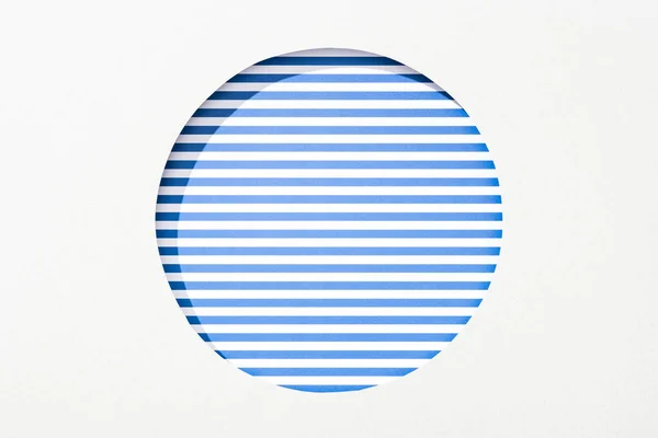 Recortar agujero redondo en papel blanco sobre fondo rayado azul y blanco - foto de stock