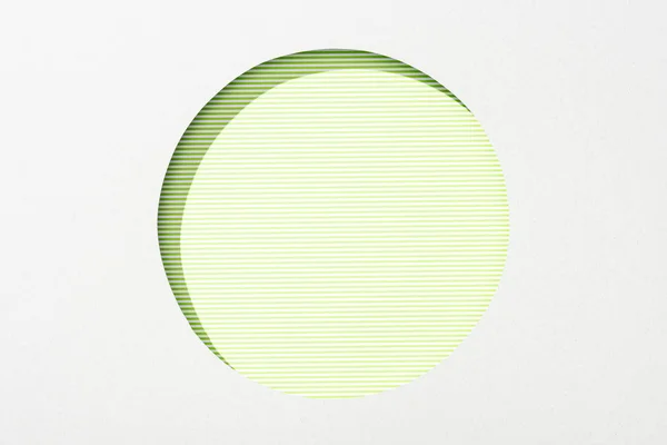 Recortar agujero redondo en papel blanco sobre fondo rayado verde lima — Stock Photo