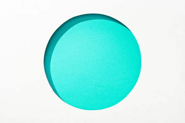 Cut out round hole in white paper on turquoise colorful background — Stock Photo