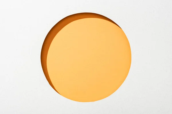 Cut out round hole in white paper on orange background — Stock Photo