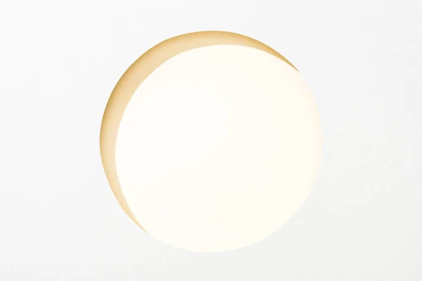 Cut out round hole in white paper on light yellow background — Stock Photo