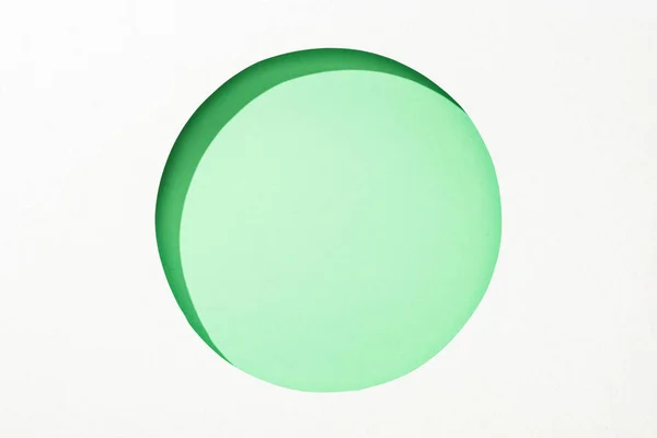 Cut out round hole in white paper on lime green colorful background — Stock Photo