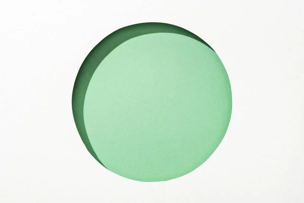 Cut out round hole in white paper on green background — Stock Photo