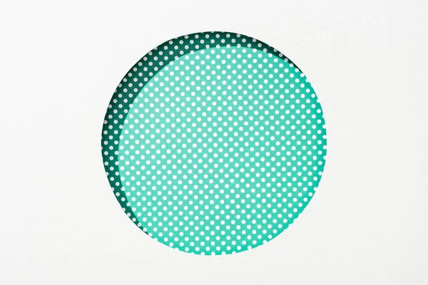 Cut out round hole in white paper on green dotted background — Stock Photo