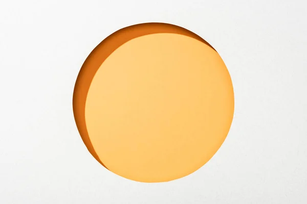 Cut out round hole in white paper on orange colorful background — Stock Photo