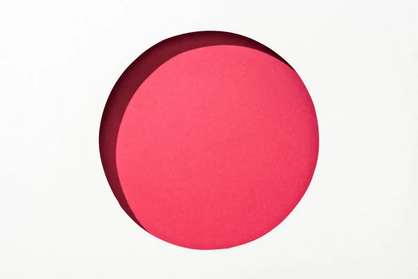 Cut out round hole in white paper on red background — Stock Photo