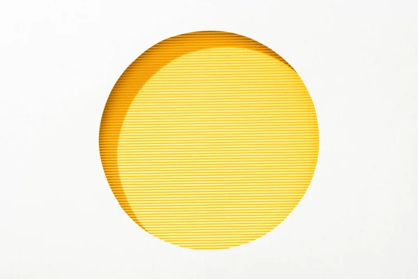 Recortar agujero redondo en papel blanco sobre fondo de color amarillo rayado - foto de stock