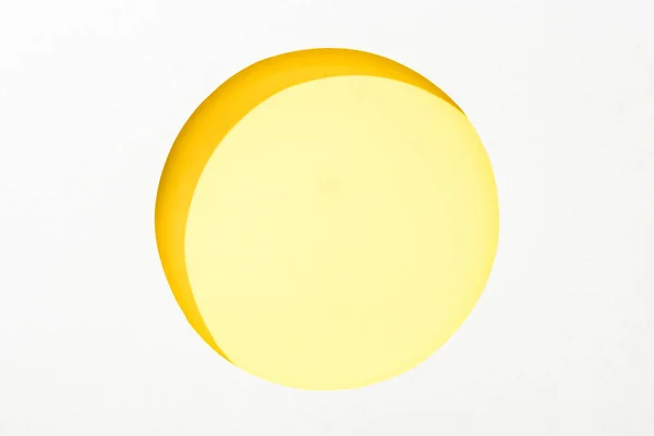 Cut out round hole in white paper on colorful yellow background — Stock Photo