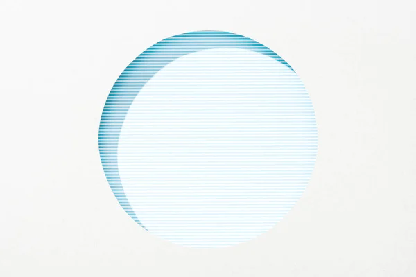 Cut out round hole in white paper on striped blue background — Stock Photo