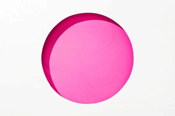 Cut out round hole in white paper on pink colorful background — Stock Photo