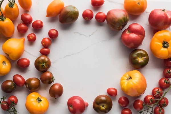 Vue de dessus des tomates éparses avec espace vide au milieu sur la surface de marbre — Photo de stock