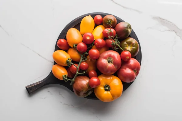 Vue de dessus des tomates sur la casserole à pizza en bois sur la surface de marbre — Photo de stock