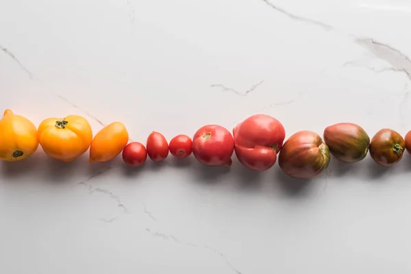 Leigos planos com tomates coloridos na superfície de mármore — Fotografia de Stock