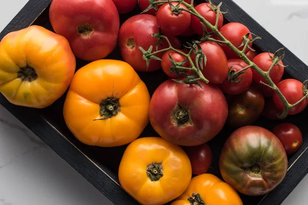 Vista superior de tomates em caixa preta de madeira na superfície de mármore — Fotografia de Stock