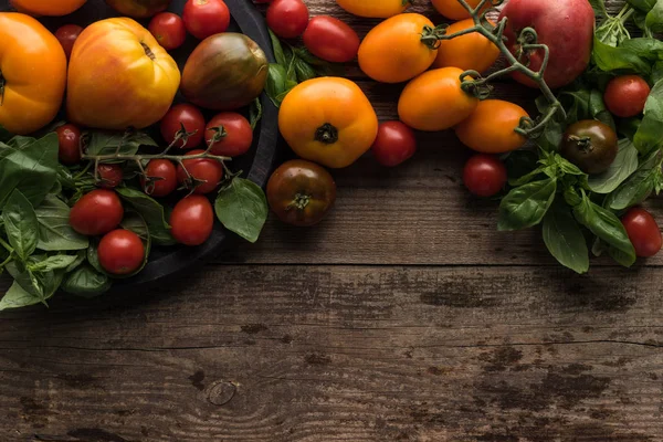 Vue du dessus des tomates éparpillées près des tomates et des épinards sur la poêle à pizza sur la table en bois — Photo de stock
