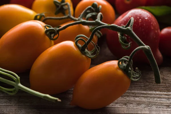 Nahaufnahme von gelben Tomaten in der Nähe roter Tomaten auf Holztisch — Stockfoto
