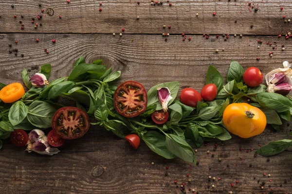 Flat lay with spinach, sliced tomatoes, garlic and scattered pepper on wooden table — Stock Photo