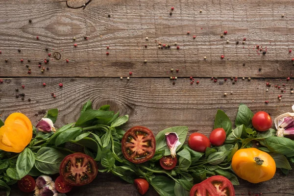 Top view of spinach, sliced tomatoes, garlic and scattered pepper on wooden table — Stock Photo