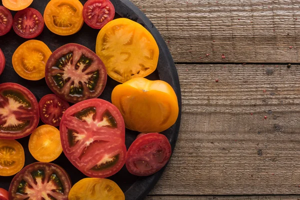 Vista superior de tomates vermelhos e amarelos fatiados na panela de pizza na superfície de madeira — Fotografia de Stock