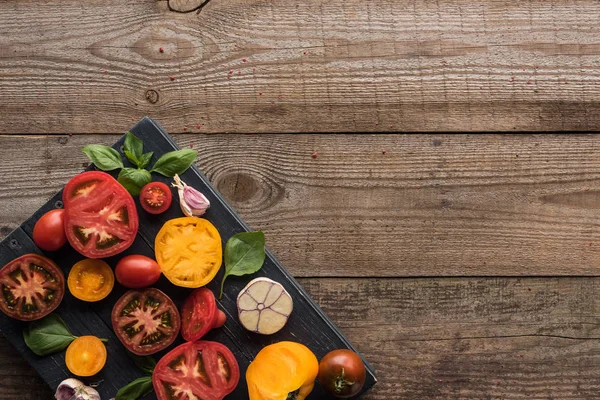 Vista superior de tomates, ajo, espinacas en bandeja sobre mesa de madera - foto de stock