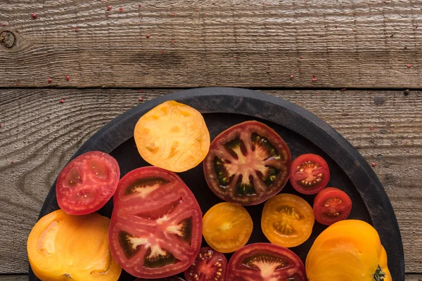 Vue de dessus des tomates rouges et jaunes tranchées sur la poêle à pizza sur la table en bois — Photo de stock