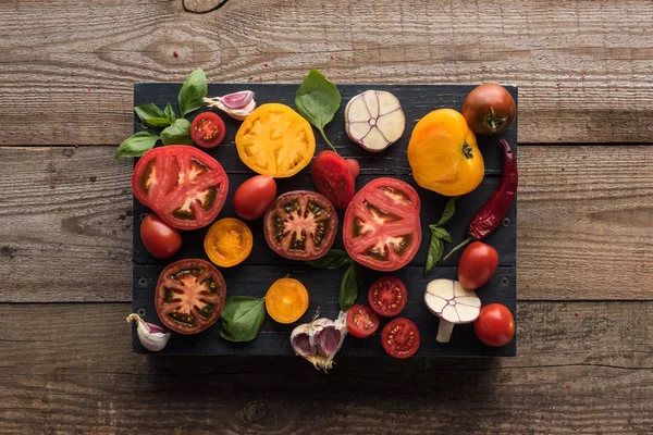 Вид зверху на помідори, часник, шпинат, перець чилі на лотку на дерев'яному столі — стокове фото