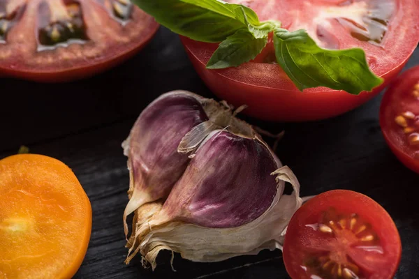 Vista ravvicinata di aglio vicino a pomodori e spinaci su vassoio di legno — Foto stock