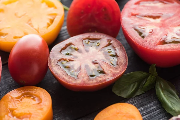 Close up view of sliced red and yellow tomatoes on black wooden tray — Stock Photo