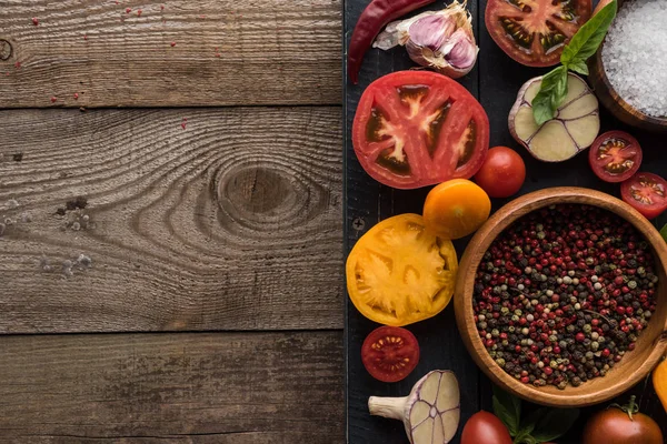 Vista superior da bandeja preta com pimenta e sal em tigelas, pimenta, tomates fatiados e alho na mesa de madeira — Fotografia de Stock