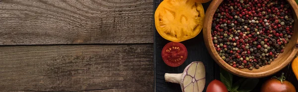 Panoramische Aufnahme eines schwarzen Tabletts mit Pfeffer und Salz in Schüsseln, Chilischote, geschnittenen Tomaten und Knoblauch auf Holztisch — Stockfoto