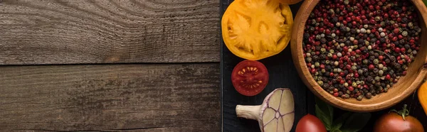 Panoramic shot of black tray with pepper and salt in bowls, chilli pepper, sliced tomatoes and garlic on wooden table — Stock Photo