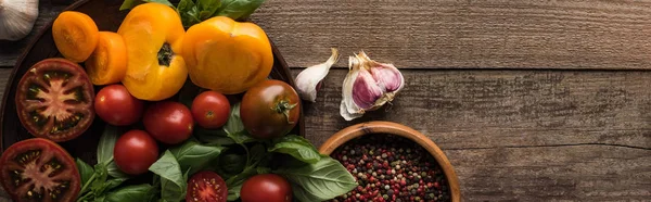 Plan panoramique d'épinards et de tomates tranchées dans une assiette près de l'ail, du piment et du bol avec du poivre sur une table en bois — Photo de stock