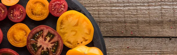 Panoramic shot of red and yellow tomatoes on pizza pan on wooden table — Stock Photo