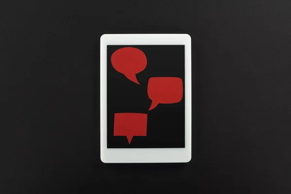 Visão superior do tablet digital com bolhas de fala vermelhas vazias no fundo preto, conceito de cyberbullying — Fotografia de Stock