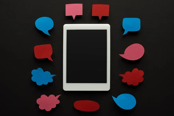 Top view of digital tablet with blank screen on black background with empty speech bubbles, cyberbullying concept — Stock Photo