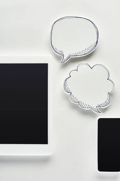 Top view of digital tablet and smartphone on white background near empty speech bubbles, cyberbullying concept — Stock Photo