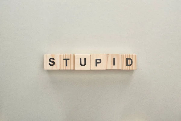 Top view of wooden blocks with stupid lettering on grey background, bullying concept — Stock Photo