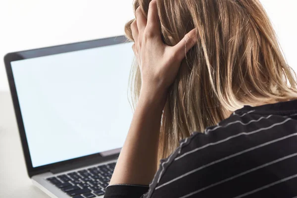 Offended blonde girl as victim of cyberbullying sitting near laptop with blank screen — Stock Photo