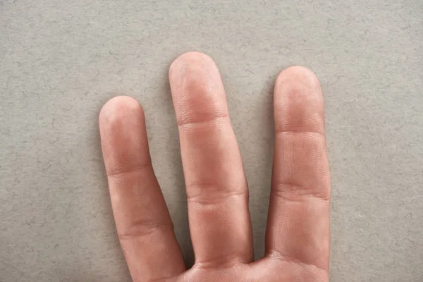 Partial view of man showing three fingers on grey background — Stock Photo