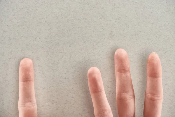 Cropped view of man showing fingers symbolizing abusers and victim on grey background — Stock Photo