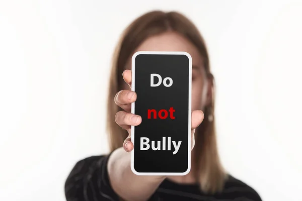Fuoco selettivo della vittima di cyberbullismo mostrando smartphone con non bullo lettering sullo schermo isolato su bianco — Foto stock