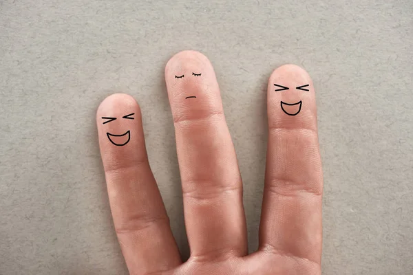 Частковий вид людини, що показує три пальці, що символізують зловмисників сміху та сумну жертву на сірому фоні — стокове фото