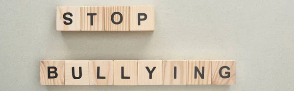 Plano panorámico de bloques de madera con letras de stop bullying sobre fondo gris - foto de stock