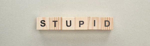 Panoramic shot of wooden blocks with stupid lettering on grey background, bullying concept — Stock Photo