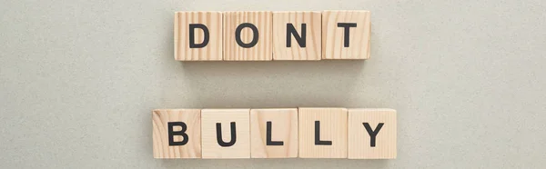 Panoramic shot of wooden blocks with dont bully lettering on grey background — Stock Photo