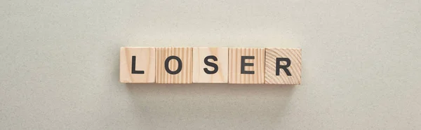 Plano panorámico de bloques de madera con palabra perdedora sobre fondo gris, concepto de intimidación - foto de stock