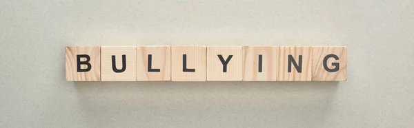 Panoramic shot of wooden blocks with bullying lettering on grey background — Stock Photo