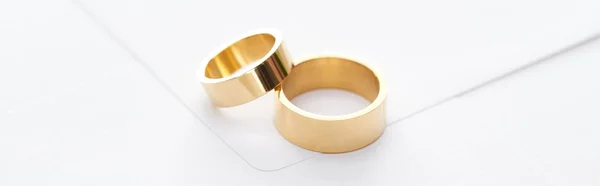 Panoramic shot of golden rings on white envelope — Stock Photo